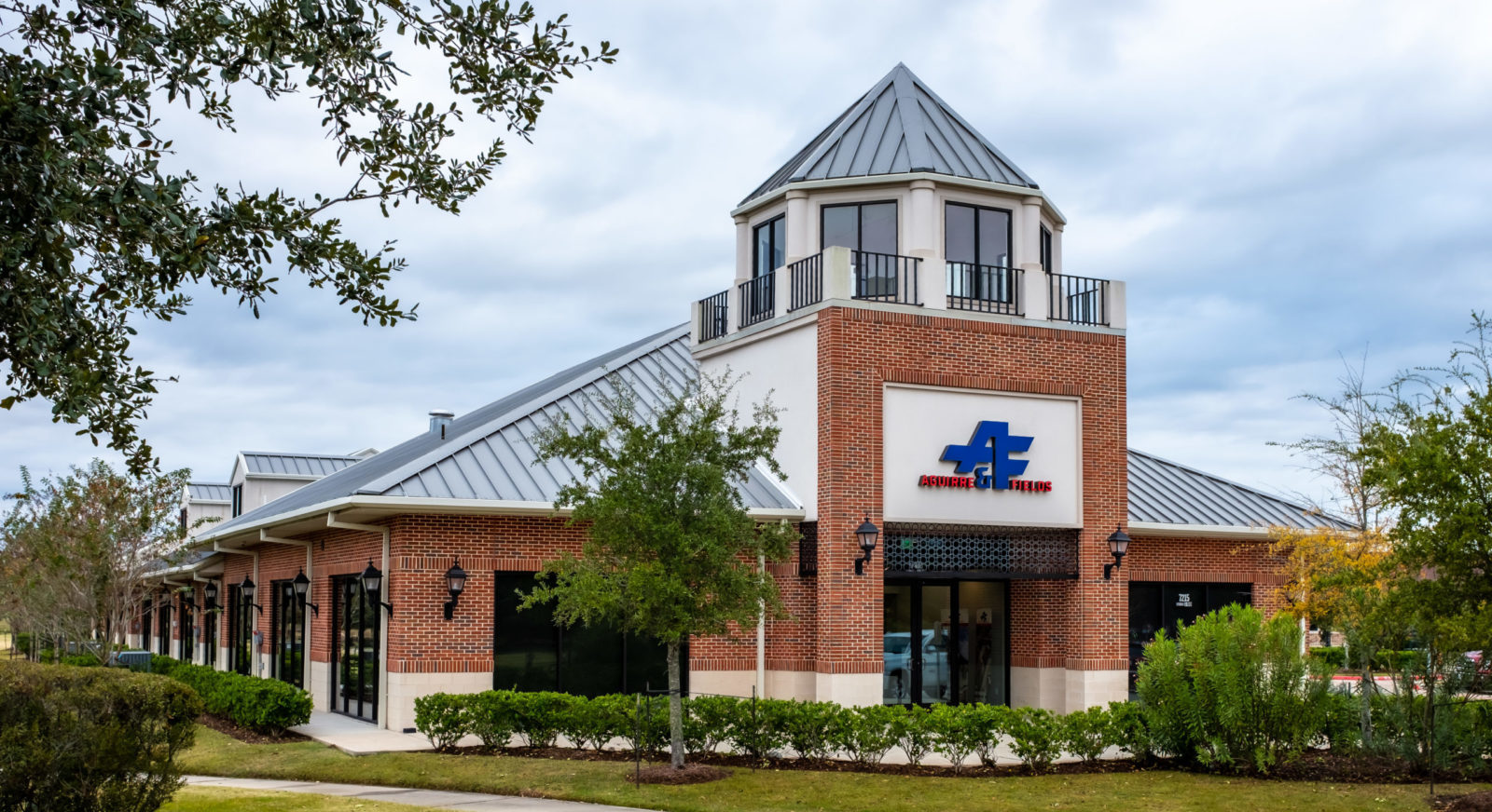 Aguirre & Fields Red Brick Building exterior with sidewalk and landscaping