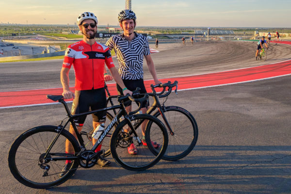 two cyclist standing with bicycles on race track