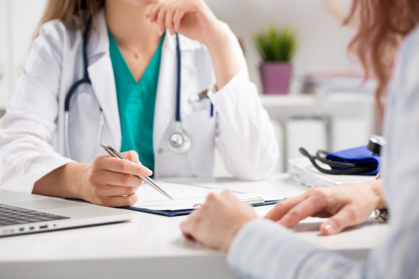 female doctor speaking to man at desk-600x400